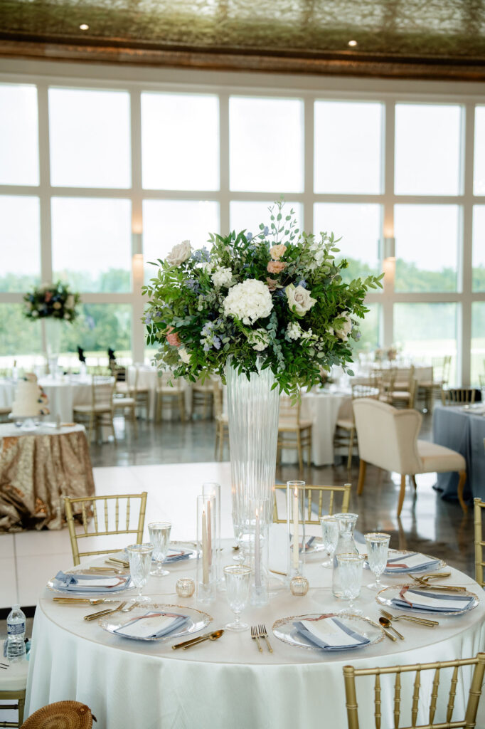Tall reception centerpiece with white, blush and blue flowers on a round wedding table.
