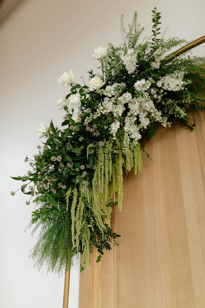 White floral and greenery installation with cascading amaranthus framing the ceremony entrance at Pear Tree Estate.